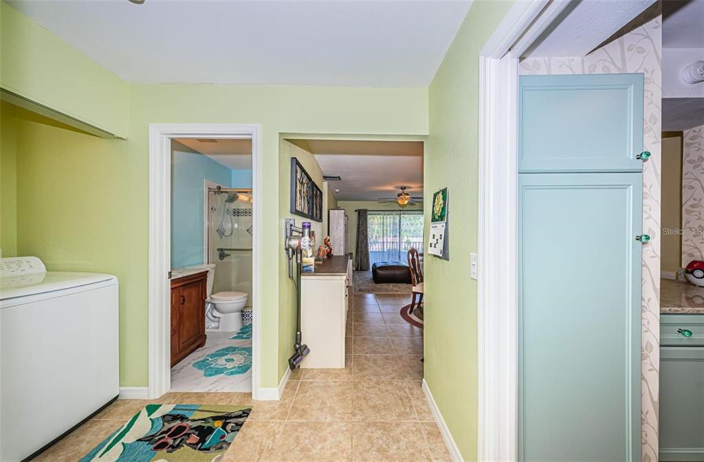 A laundry area with a washer leads to a bathroom and a living space beyond — 2117 LAKEWOOD CLUB DRIVE S UNIT 7K, ST PETERSBURG, FL