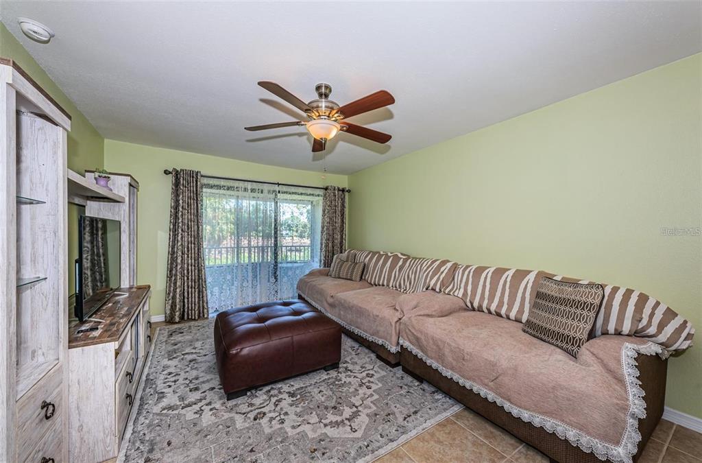 A living room features a large sectional sofa, a leather ottoman, and a ceiling fan — 2117 LAKEWOOD CLUB DRIVE S UNIT 7K, ST PETERSBURG, FL