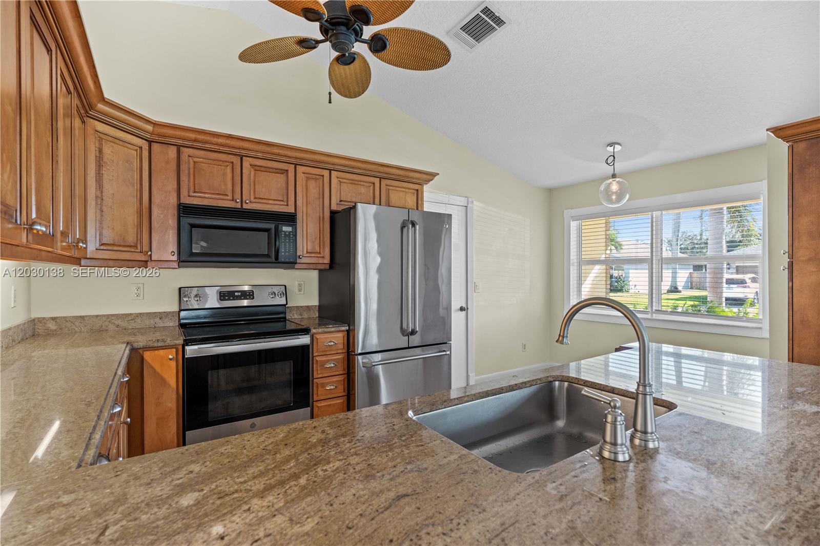 A kitchen features wood cabinets, granite countertops, stainless steel appliances, and a central island sink — 132 Wandering Trl, Jupiter FL 33458, JUPITER, FL