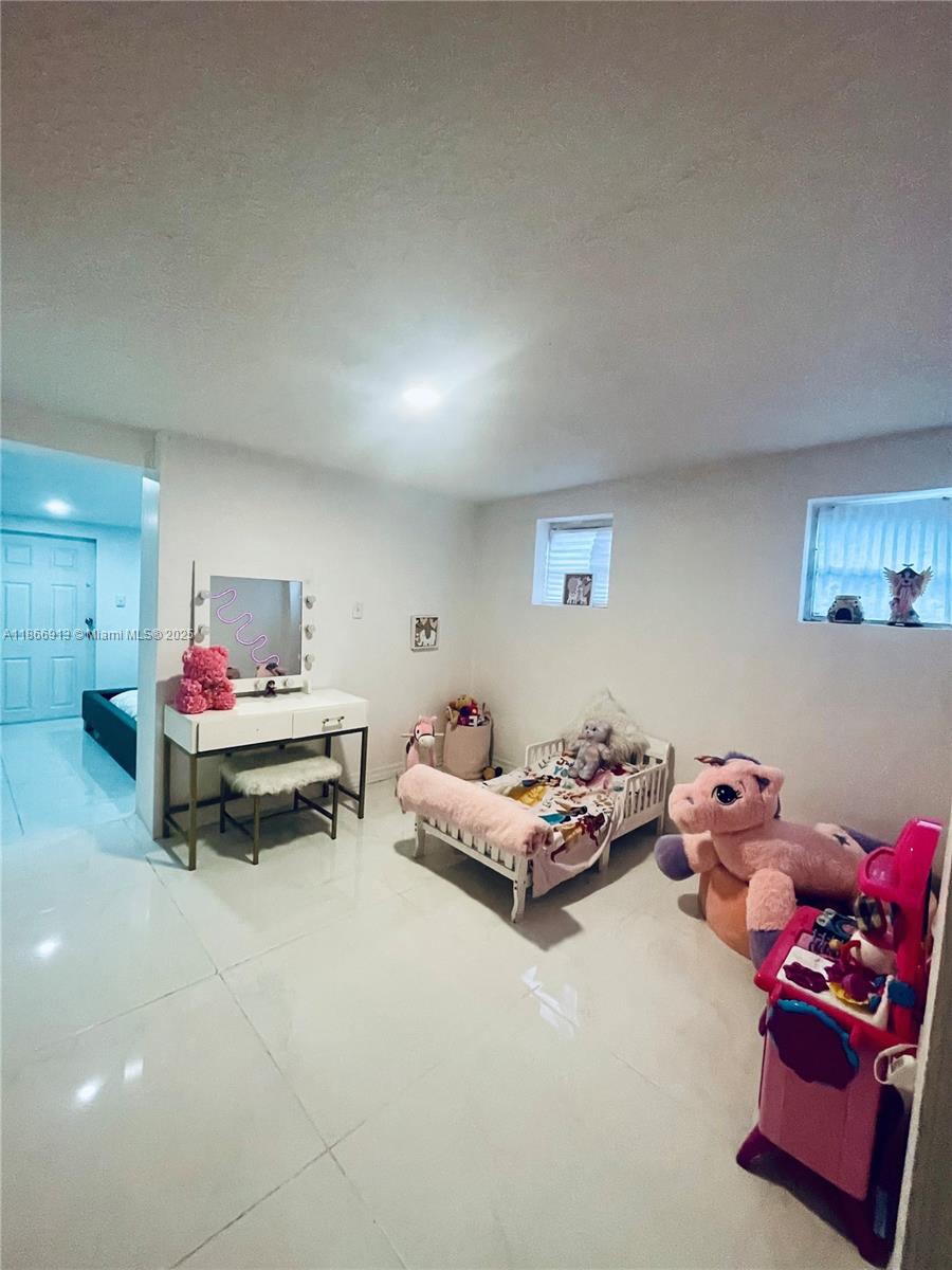 A child's bedroom features white tile floors, a small bed, a vanity, and plush toys — 2751 NW 99th St, Miami FL 33147, MIAMI, FL