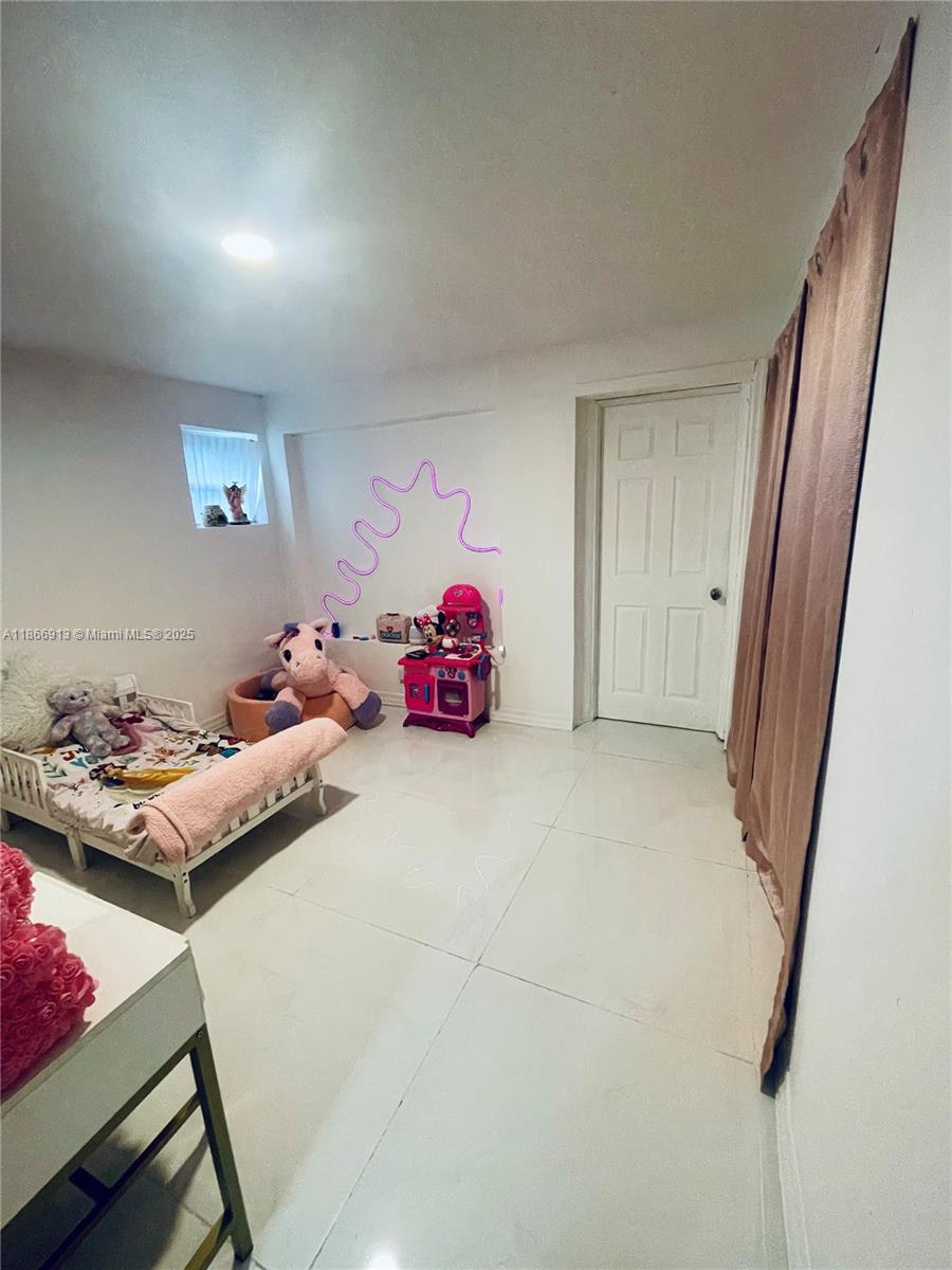 A child's bedroom features white tile flooring, a small bed, and a toy kitchen — 2751 NW 99th St, Miami FL 33147, MIAMI, FL