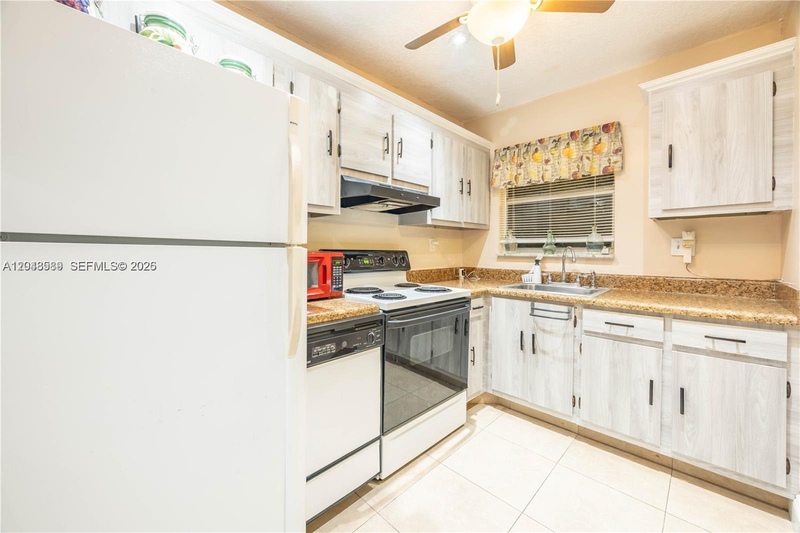 A kitchen features light wood-grain cabinets, granite countertops, a white refrigerator, and white appliances — 2811 N Pine Island Rd # 309, Sunrise FL 33322, SUNRISE, FL