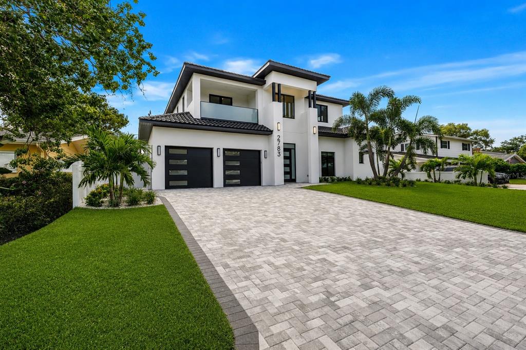 A modern two-story house with a paved driveway, two-car garage, and a second-floor balcony — 2783 67TH WAY N, ST PETERSBURG, FL