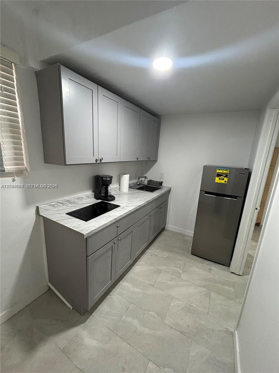 This kitchen features gray cabinets, a marble-patterned countertop, a cooktop, and a stainless steel refrigerator — 6773 Dogwood Dr # 1, Miramar FL 33023, MIRAMAR, FL
