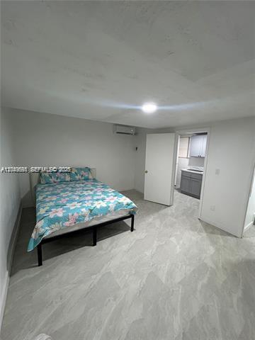 A bedroom with a bed, light gray tile flooring, and an adjacent small kitchen area — 6773 Dogwood Dr # 1, Miramar FL 33023, MIRAMAR, FL