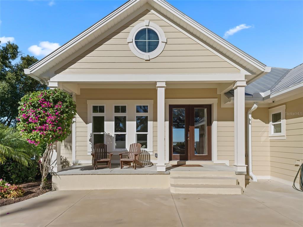 A tan house with a metal roof, three-car garage, and a basketball hoop in the driveway — 12943 SE SUNSET HARBOR ROAD, WEIRSDALE, FL