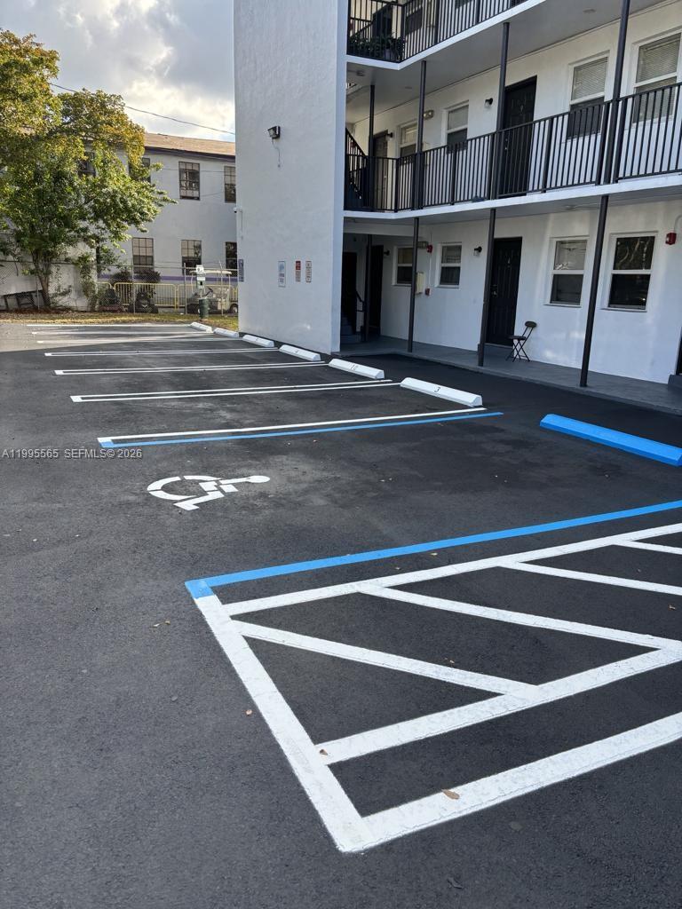 An exterior view of an apartment building with a designated handicap parking space — 1130 NW 62nd St # 15, Miami FL 33150, MIAMI, FL