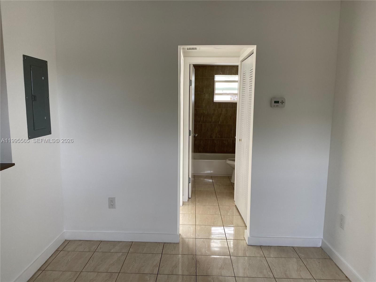 A room with tiled floors leads into a bathroom featuring a tub and shower — 1130 NW 62nd St # 15, Miami FL 33150, MIAMI, FL