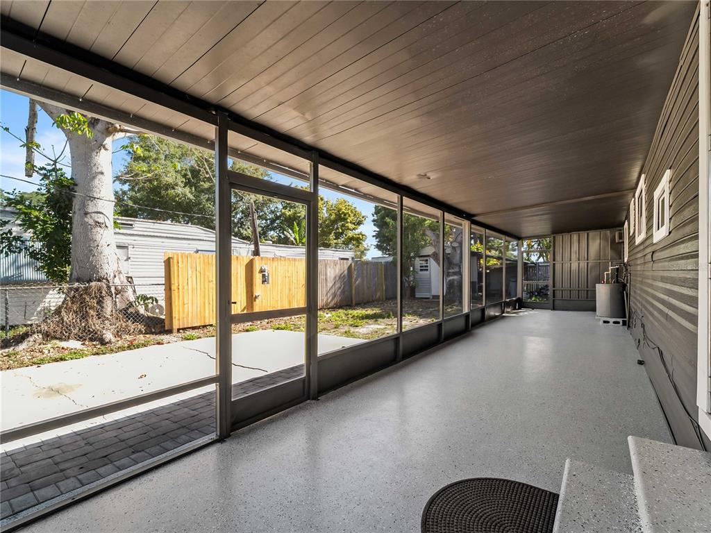 A screened-in porch features a gray speckled floor, dark wood-paneled ceiling, and a screen door — 110 VERONA STREET N, NOKOMIS, FL