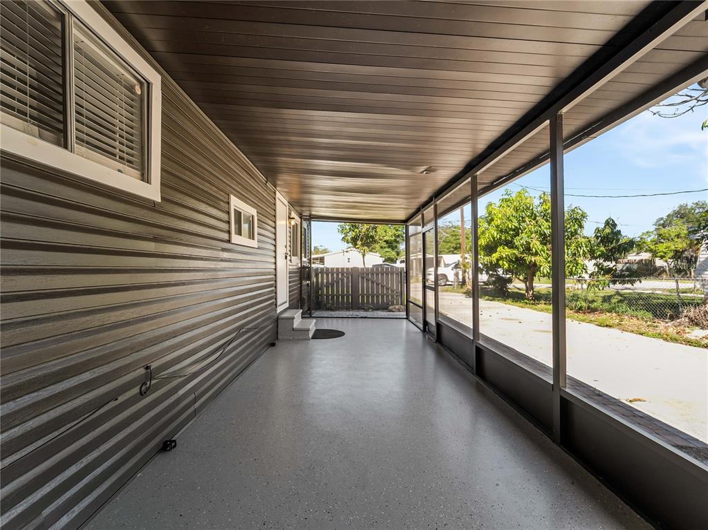 A covered outdoor patio features gray flooring, dark siding, and screened-in walls — 110 VERONA STREET N, NOKOMIS, FL