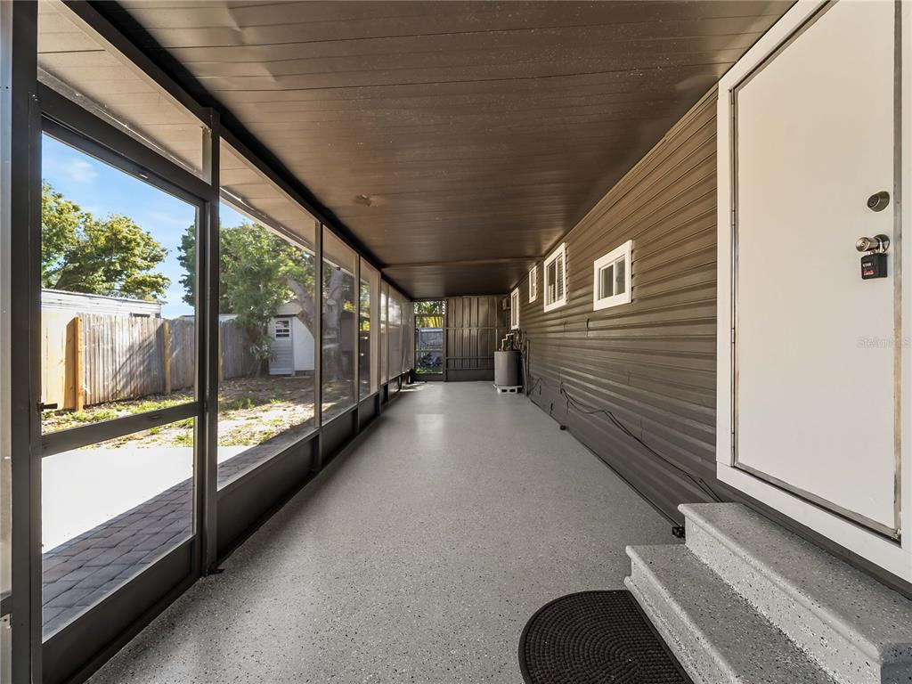 A long, covered screened-in porch features gray epoxy flooring and dark horizontal siding — 110 VERONA STREET N, NOKOMIS, FL