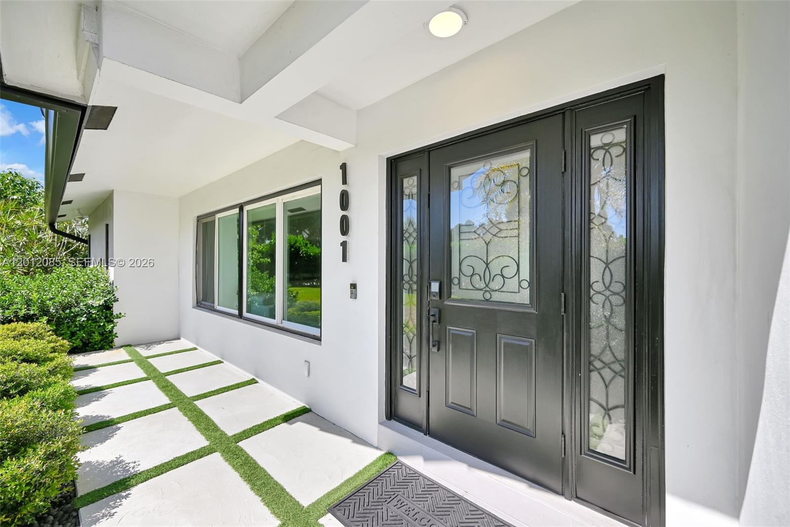 The front entrance features a black door with glass inserts and a paved walkway — 1001 NW 4th Ct, Boca Raton FL 33432, BOCA RATON, FL