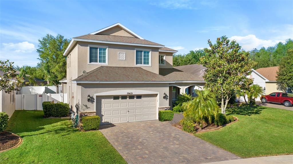 A two-story suburban house with a tan stucco exterior, a paved driveway, and a garage — 19419 RED SKY COURT, LAND O LAKES, FL