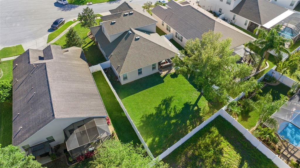 An aerial view shows two suburban houses with fenced backyards and a shared green space — 19419 RED SKY COURT, LAND O LAKES, FL