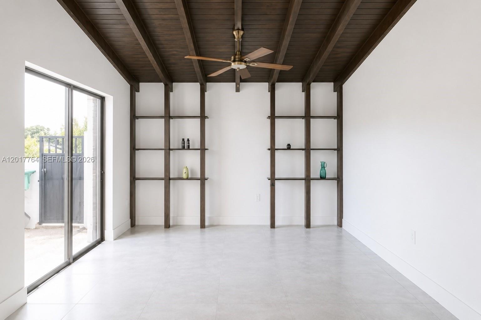 A bright room features a dark wood-beamed ceiling, built-in shelving, and a sliding glass door — 6603 SW 112th Pl, Miami FL 33173, MIAMI, FL