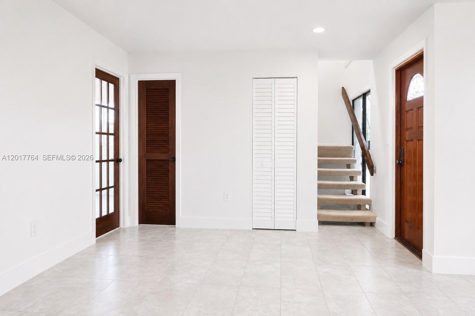 A bright entryway features white walls, tile flooring, two wooden doors, a closet, and stairs — 6603 SW 112th Pl, Miami FL 33173, MIAMI, FL