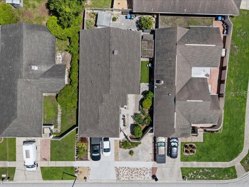 An aerial view shows three suburban houses with driveways, roofs, and small backyard green spaces — 10903 LANDON LANE, TAMPA, FL