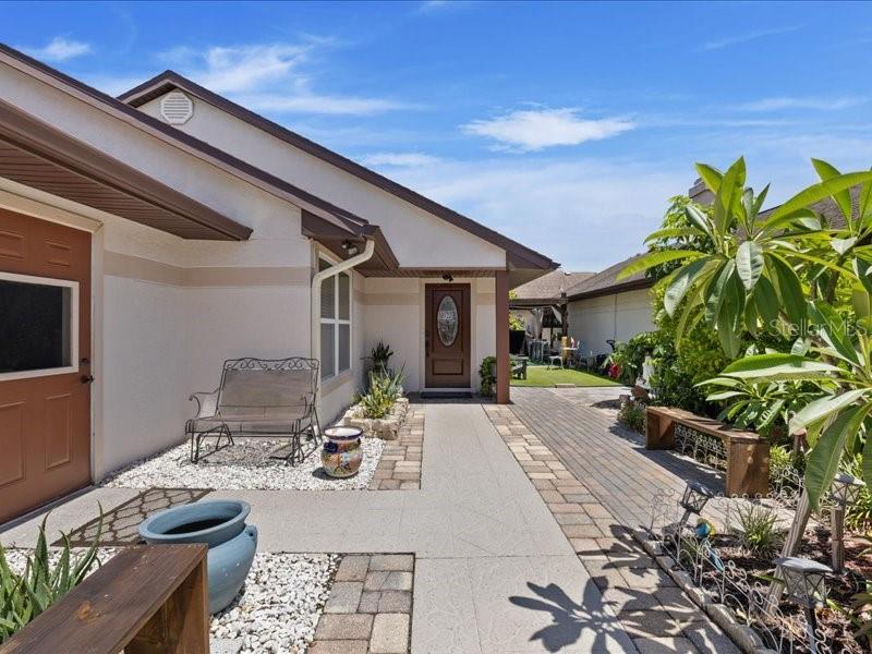 A paved walkway leads to the front entrance of a house with a metal bench — 10903 LANDON LANE, TAMPA, FL