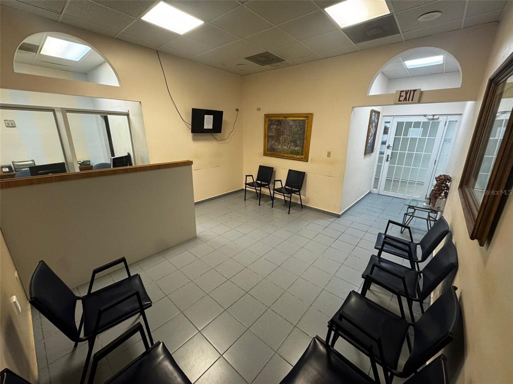 A waiting room with tiled floors, black chairs, a reception desk, and an exit door — 204 CALLE JULIO CINTRON, AIBONITO, PR