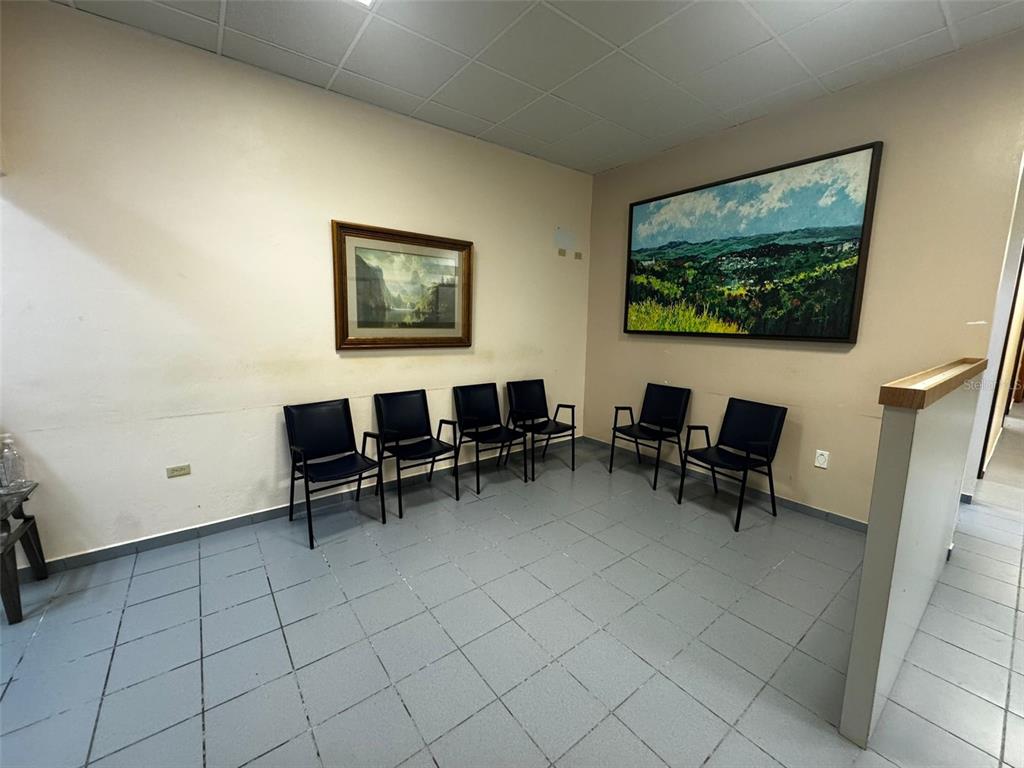 A waiting room with six black chairs, tiled flooring, and two framed landscape paintings — 204 CALLE JULIO CINTRON, AIBONITO, PR