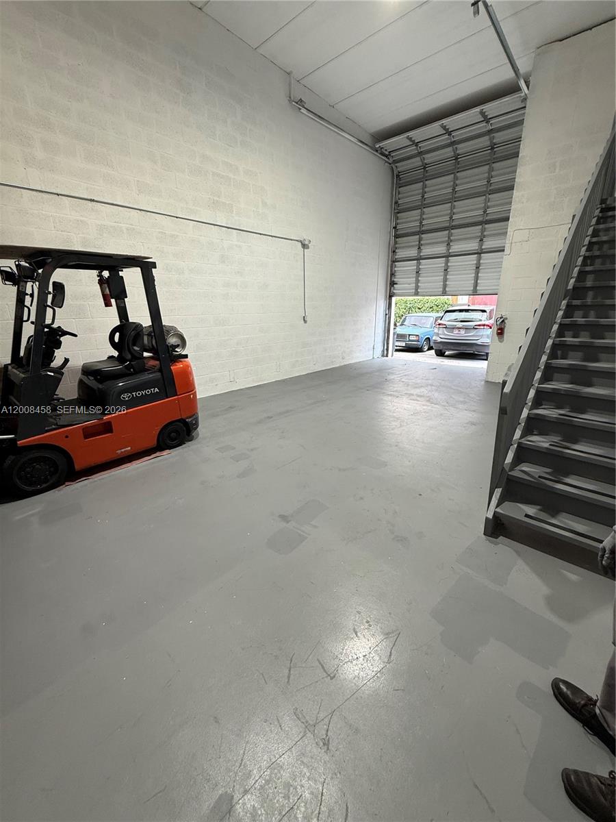 An industrial warehouse space features a gray concrete floor, a forklift, and metal stairs — 13355 SW 135th Ave # 12, Miami FL 33186, MIAMI, FL