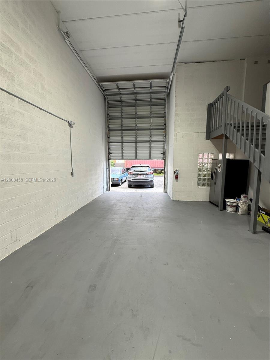 This industrial warehouse space features a roll-up door, concrete walls, and a staircase — 13355 SW 135th Ave # 12, Miami FL 33186, MIAMI, FL