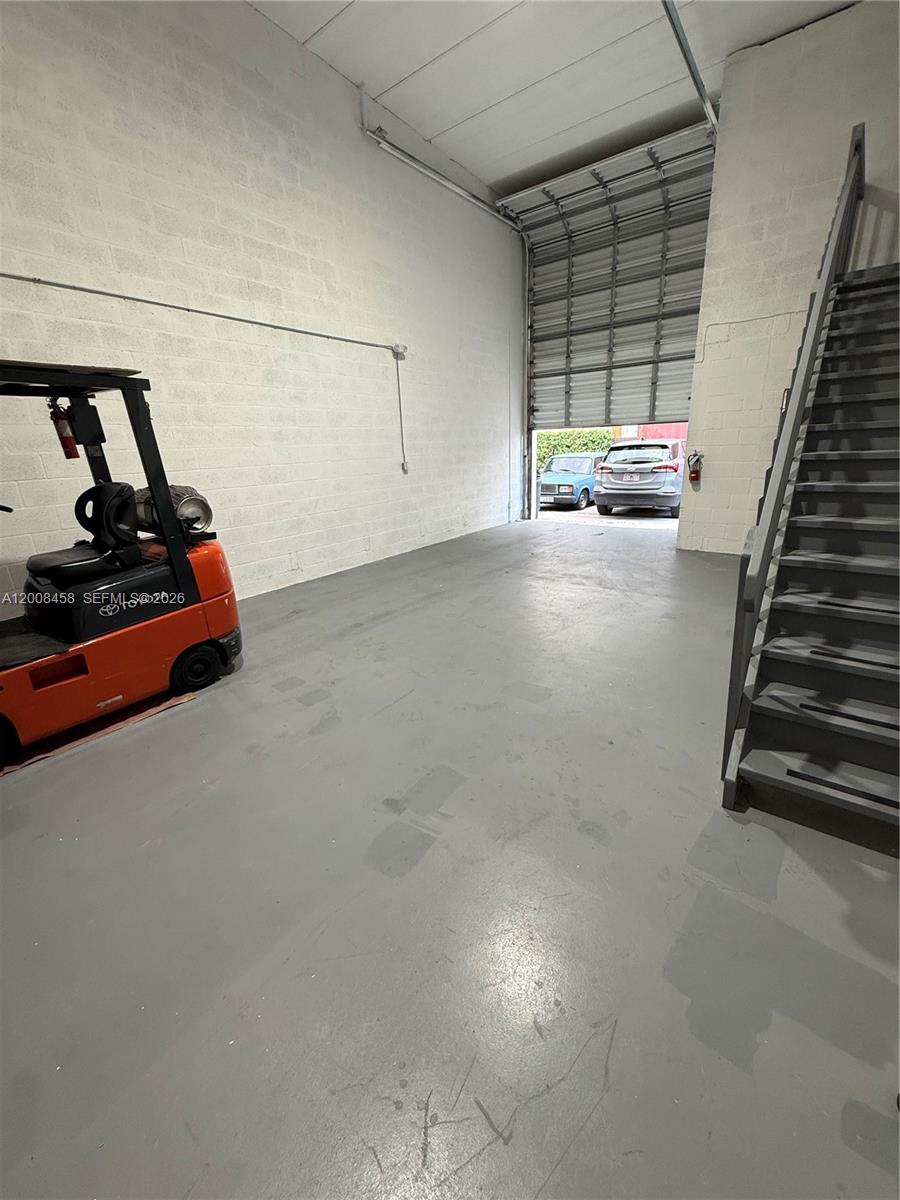 An industrial warehouse space features a concrete floor, a forklift, and a metal staircase — 13355 SW 135th Ave # 12, Miami FL 33186, MIAMI, FL