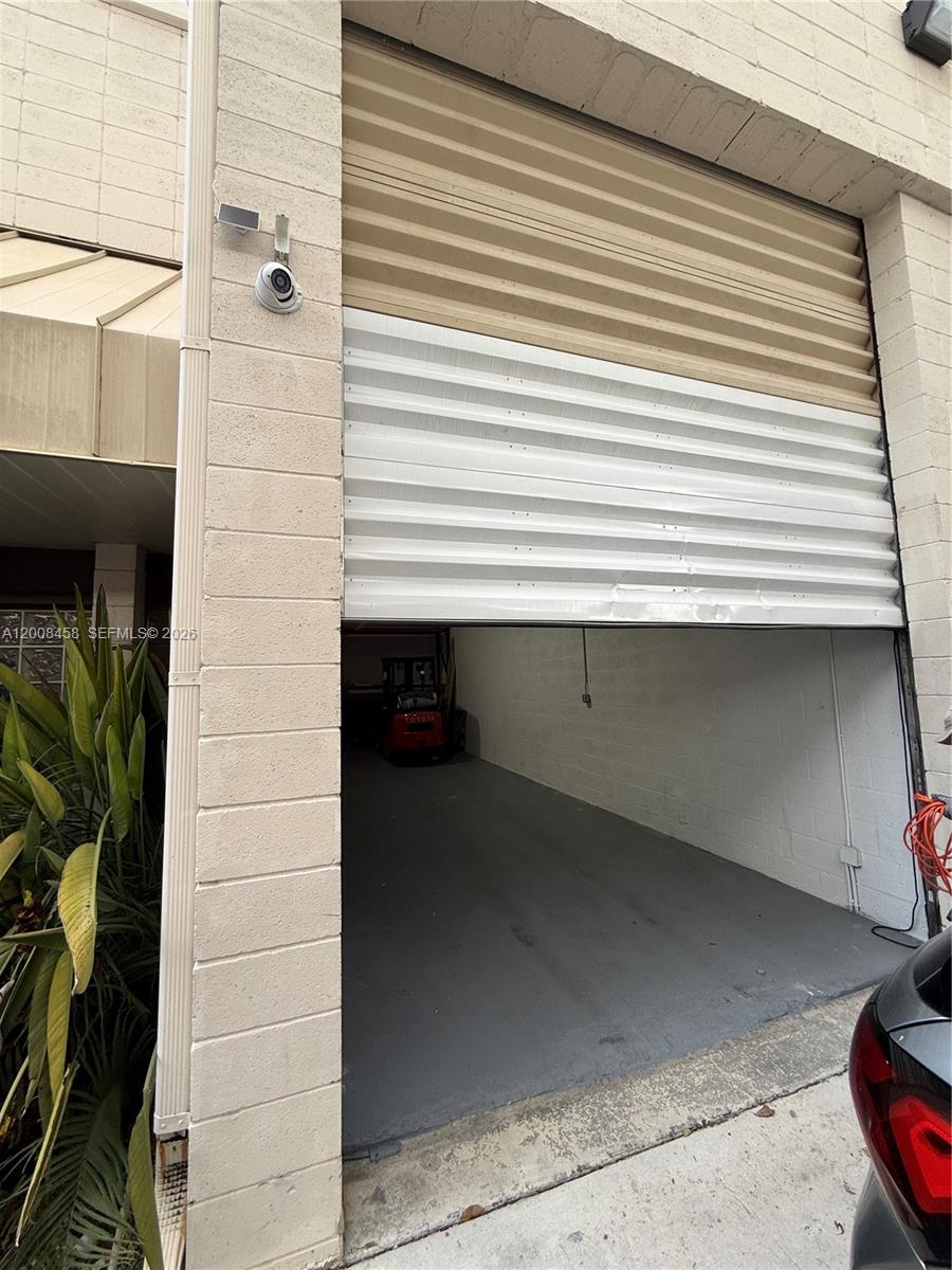 A view of an open roll-up garage door revealing a concrete-floored storage space — 13355 SW 135th Ave # 12, Miami FL 33186, MIAMI, FL