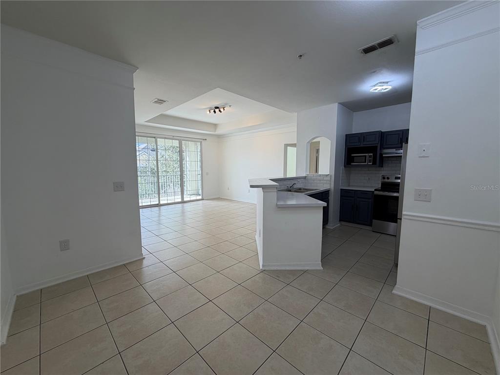 An open-concept living area features tile flooring, a kitchen with dark cabinets, and sliding doors — 3315 PARKCHESTER SQUARE BOULEVARD UNIT 301, ORLANDO, FL