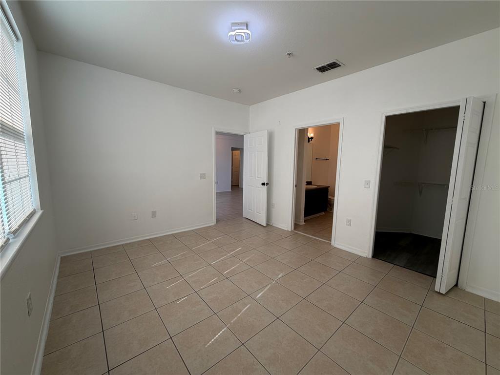 An empty bedroom with tile flooring, a walk-in closet, and an attached bathroom — 3315 PARKCHESTER SQUARE BOULEVARD UNIT 301, ORLANDO, FL