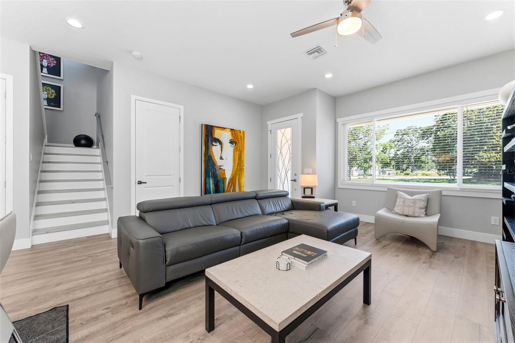 A living room features a grey sectional sofa, a coffee table, and stairs leading upward — 112 W SLIGH AVENUE, TAMPA, FL