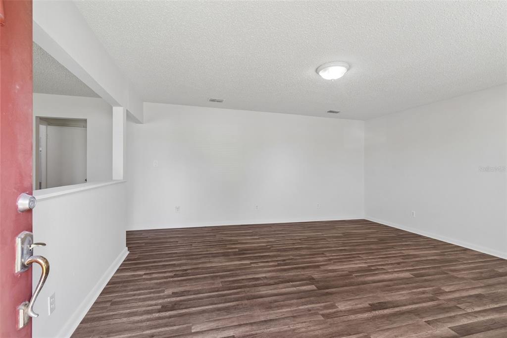 An empty room features white walls, a textured ceiling, and dark wood-look flooring — 6711 INTERBAY BOULEVARD, TAMPA, FL