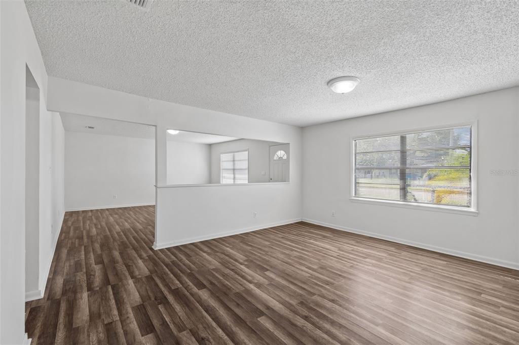 A living room with wood-look flooring, white walls, and a large interior pass-through window — 6711 INTERBAY BOULEVARD, TAMPA, FL