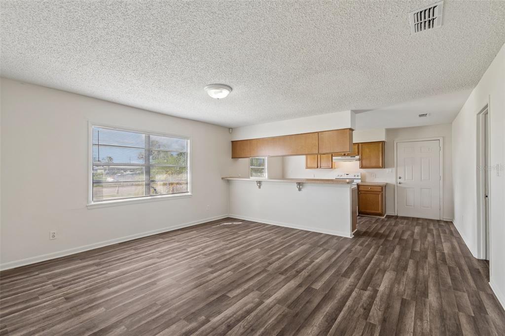An open-concept living area features wood-look flooring, a breakfast bar, and a kitchen with cabinets — 6711 INTERBAY BOULEVARD, TAMPA, FL