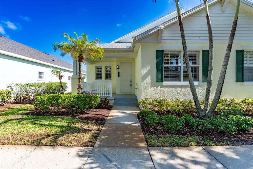 A light yellow house with a covered porch, green shutters, and a palm tree — 7534 15TH LANE, VERO BEACH, FL