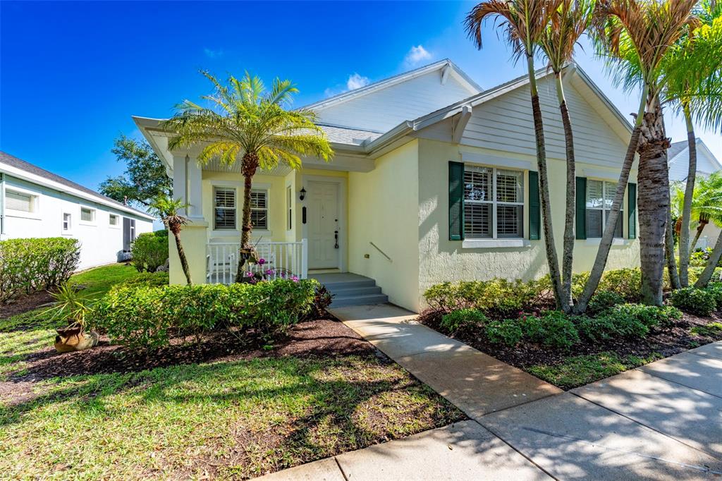A pale yellow house with dark green shutters and a front porch with palm trees — 7534 15TH LANE, VERO BEACH, FL