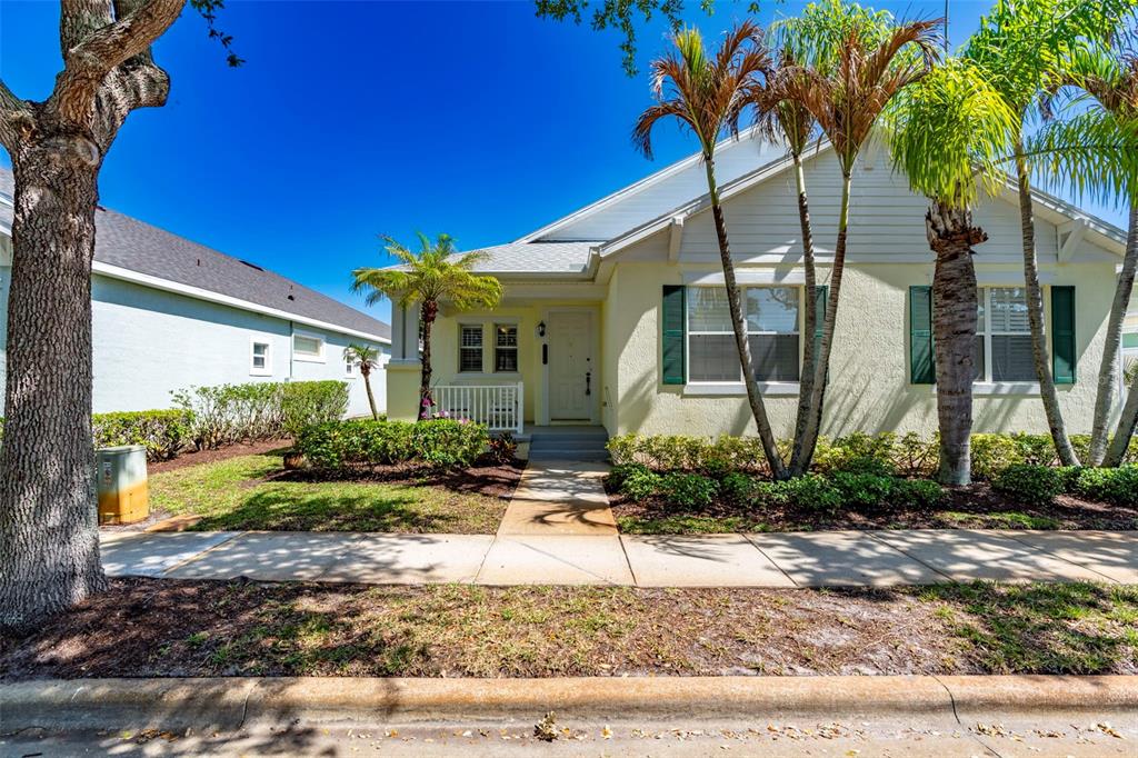 A single-story house with light yellow siding, green shutters, and palm trees in the front yard — 7534 15TH LANE, VERO BEACH, FL