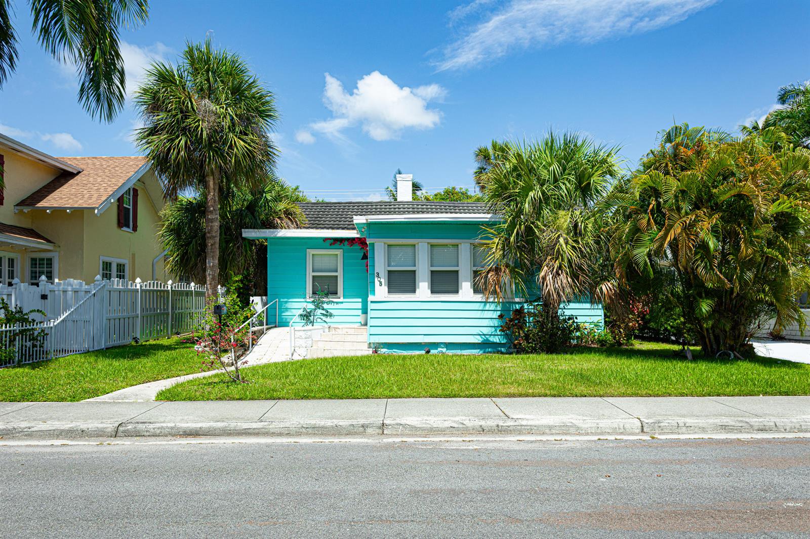 A bright turquoise, single-story house with a white ramp and palm trees in the front yard — 305 N Lakeside Drive, FL 33460, FL