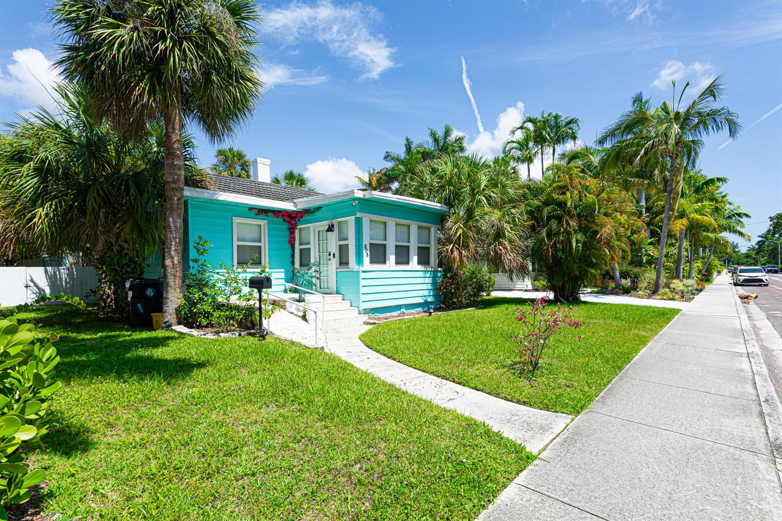 A turquoise, single-story house with a white front porch sits behind a green lawn — 305 N Lakeside Drive, FL 33460, FL