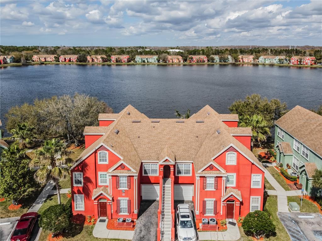 An aerial view shows a red multi-unit residential building situated along a lake — 9632 LAKE CHASE ISLAND WAY UNIT 9632, TAMPA, FL
