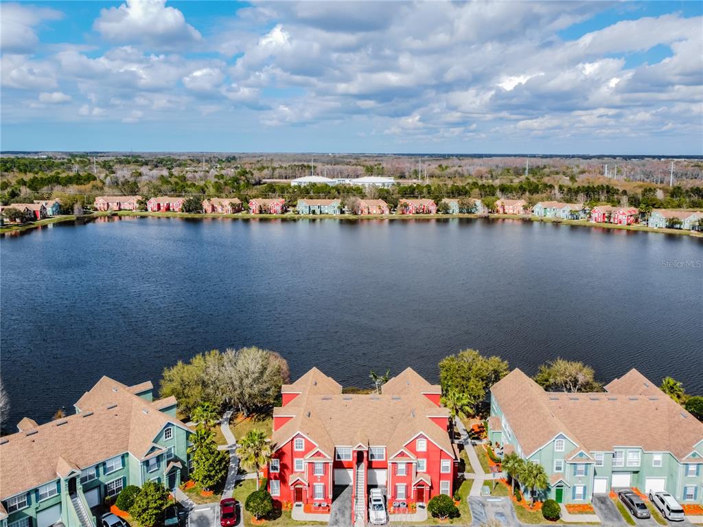 An aerial view shows several multi-story apartment buildings surrounding a large lake under a cloudy sky — 9632 LAKE CHASE ISLAND WAY UNIT 9632, TAMPA, FL