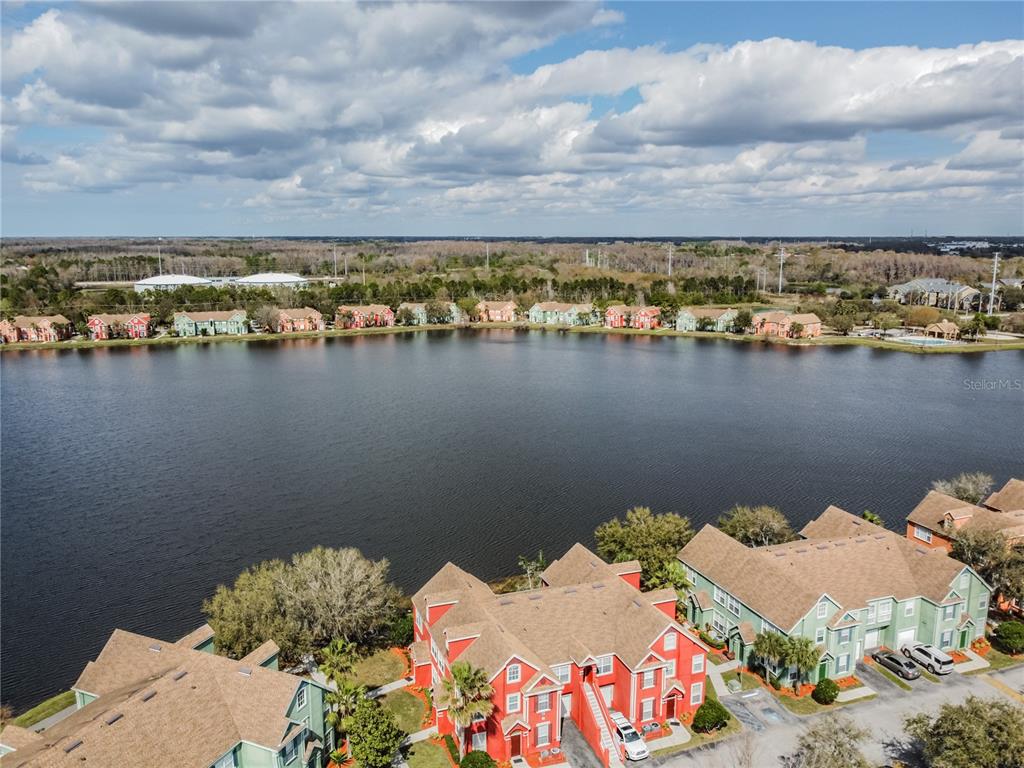 An aerial view shows multi-story apartment buildings situated along the shore of a lake — 9632 LAKE CHASE ISLAND WAY UNIT 9632, TAMPA, FL