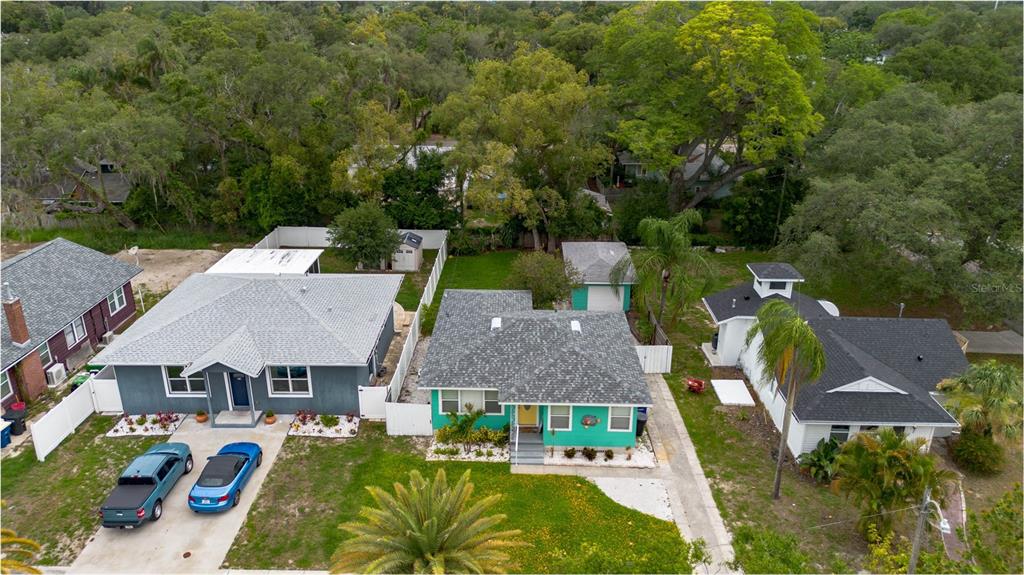 An aerial view shows three residential houses with driveways and yards in a wooded neighborhood — 1226 SEDEEVA CIRCLE S, CLEARWATER, FL