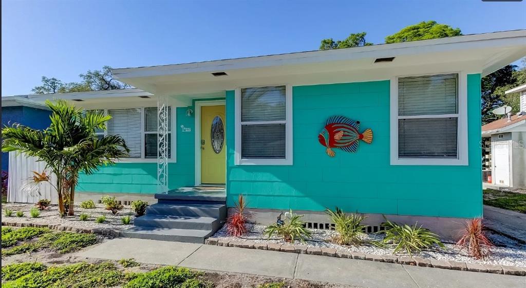 A turquoise house with a yellow front door, white trim, and a decorative fish wall hanging — 1226 SEDEEVA CIRCLE S, CLEARWATER, FL