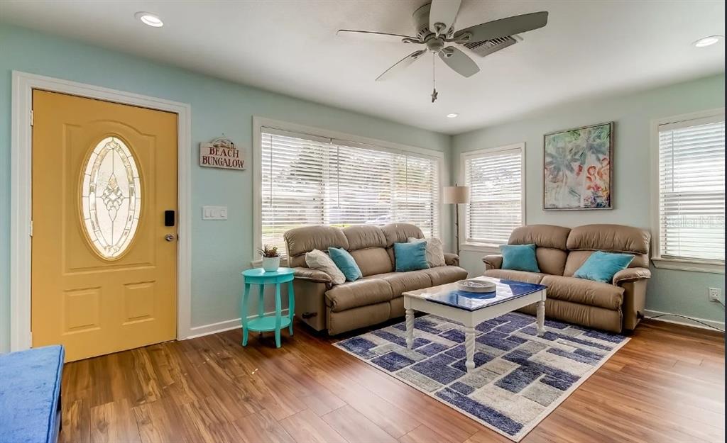 A living room with light blue walls, a yellow front door, and two brown sofas — 1226 SEDEEVA CIRCLE S, CLEARWATER, FL