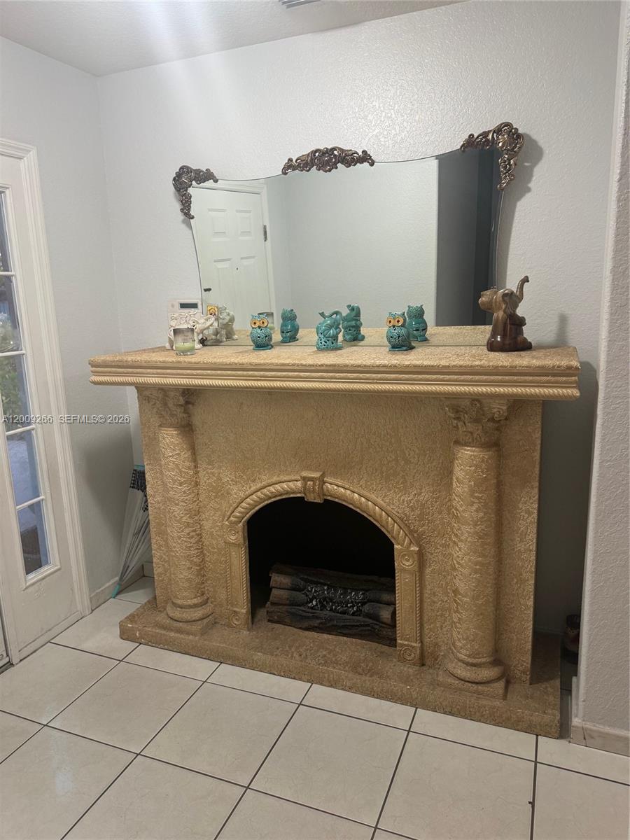 A textured, column-style fireplace mantel with a large decorative mirror sits on a tiled floor — 8748 NW 143rd Ter, Miami Lakes FL 33018, MIAMI LAKES, FL