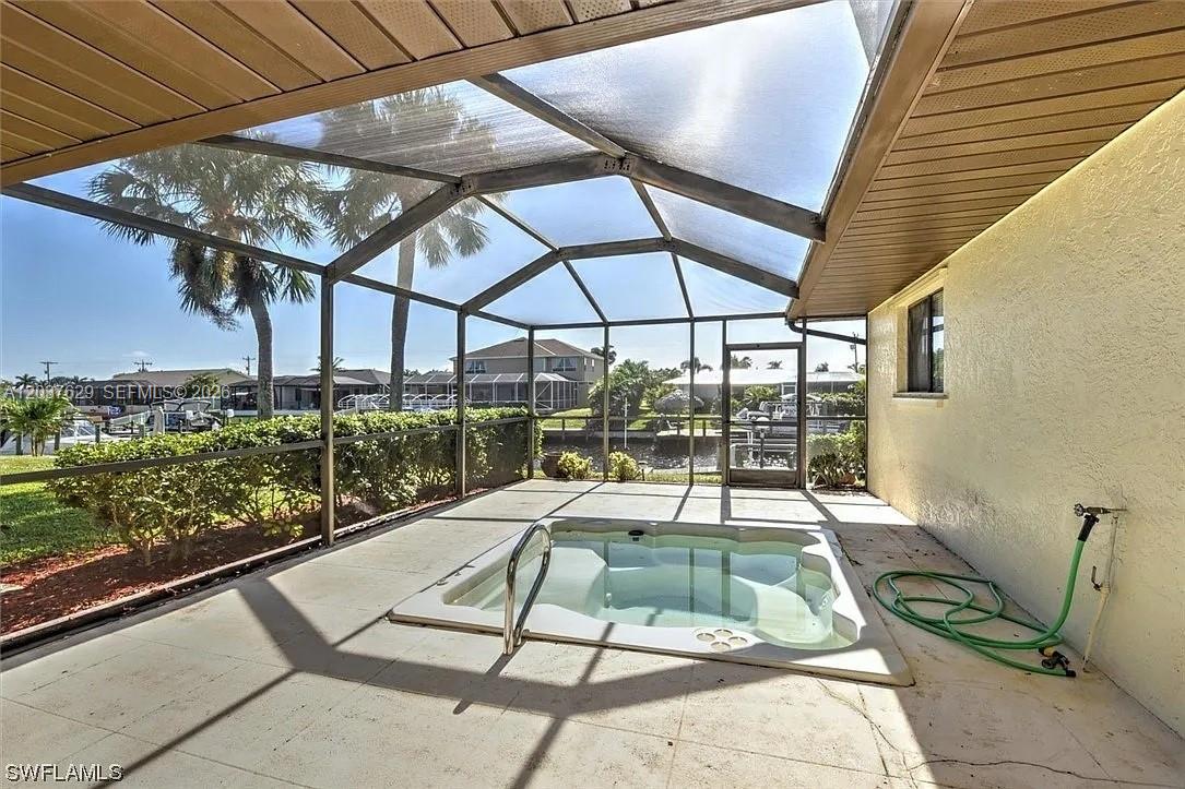 A screened-in patio features a built-in hot tub and views of a canal — 1822 SE 11 Ter, Cape Coral FL 33990, CAPE CORAL, FL