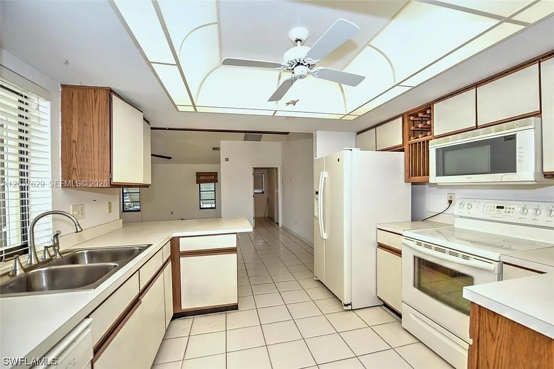 A kitchen with white appliances, light-colored cabinets, tiled floors, and a ceiling fan — 1822 SE 11 Ter, Cape Coral FL 33990, CAPE CORAL, FL