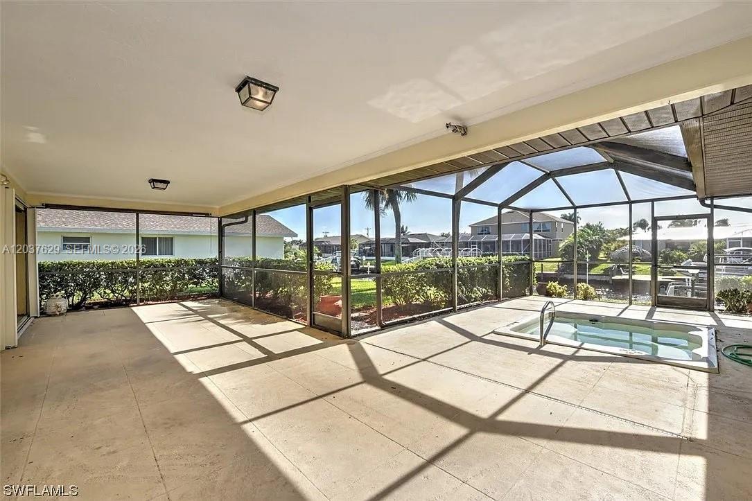 A screened-in patio features a built-in hot tub and tile flooring overlooking a canal — 1822 SE 11 Ter, Cape Coral FL 33990, CAPE CORAL, FL