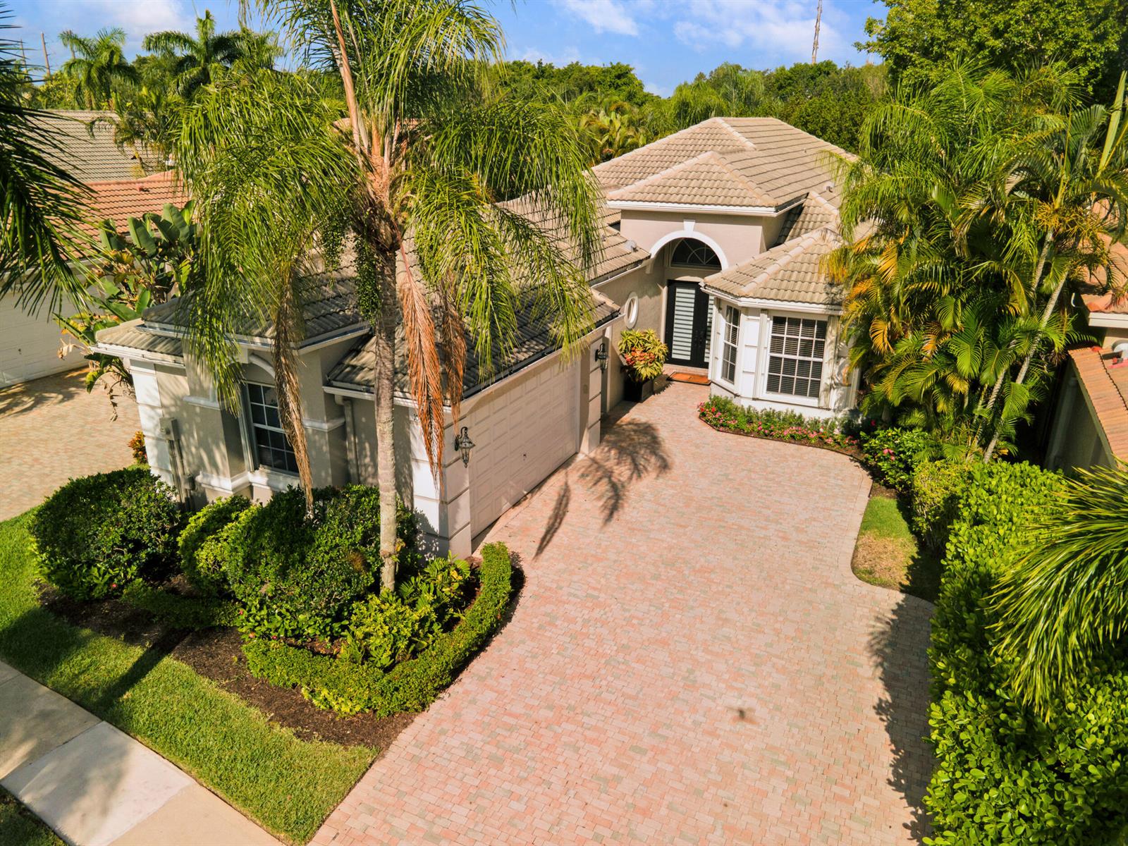 An aerial view of a single-story house with a paved driveway and lush tropical landscaping — 10916 Northgreen Drive, Lake Worth FL 33449, LAKE WORTH, FL